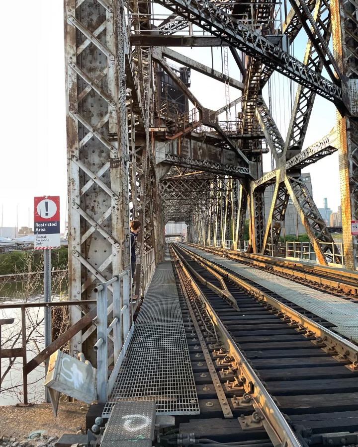 Photograph of a railroad track bridge and a sign to the side reading "restricted area"