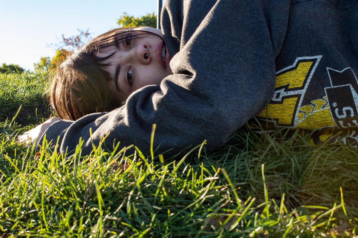 photograph of a girl laying in the green grass