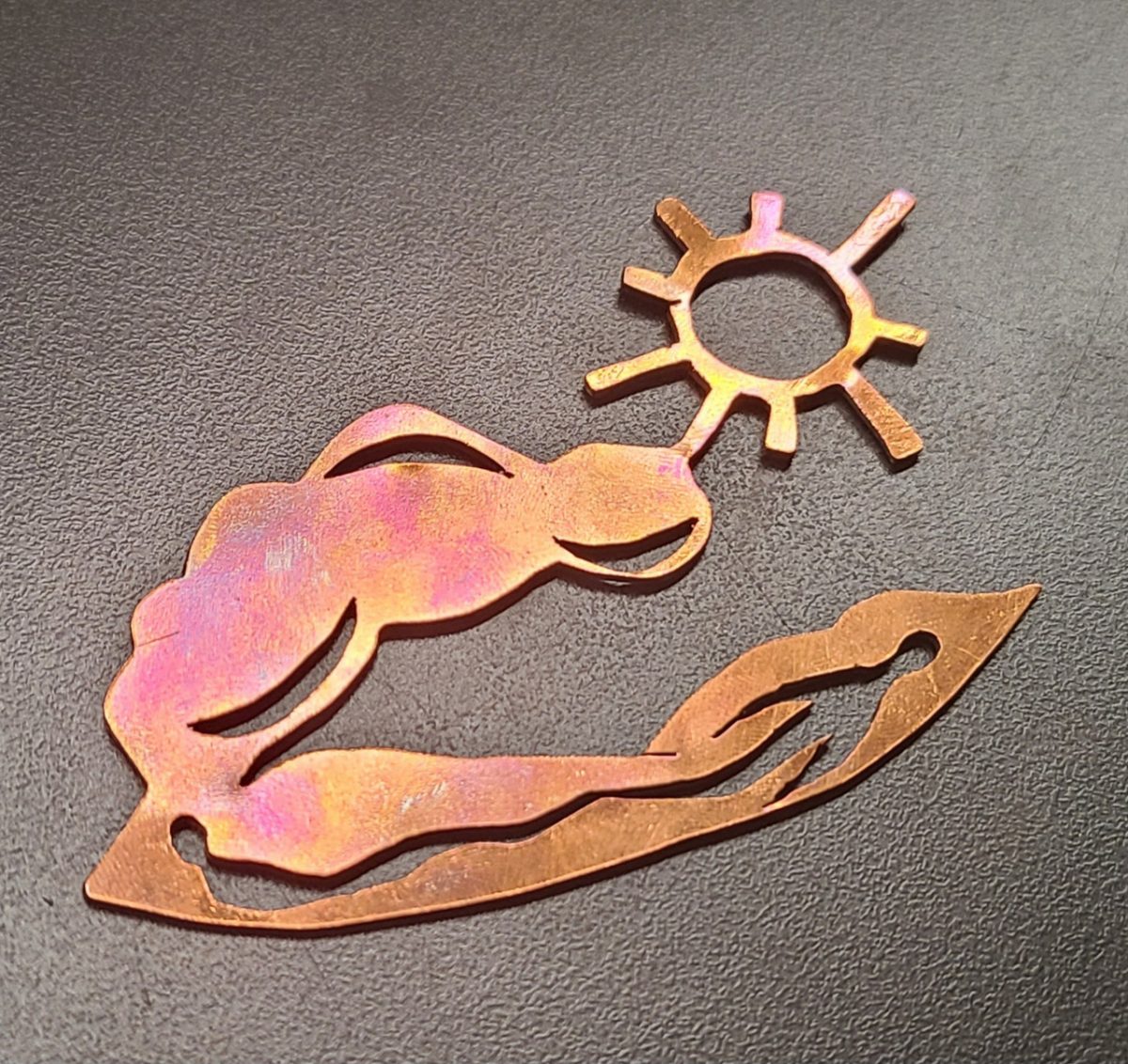 A metal piece that reflects Aztec symbolism and myth, with a red patina.