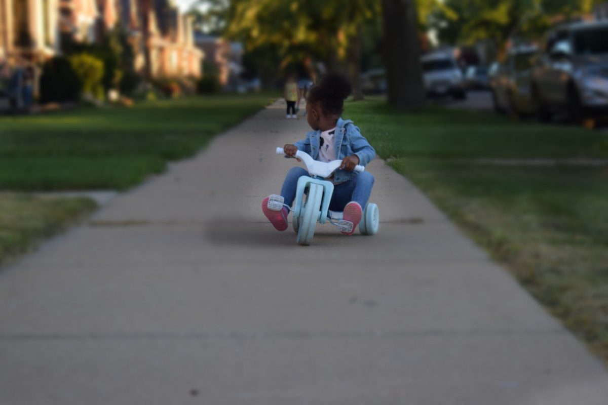 Little girl on a toy on the sidewalk