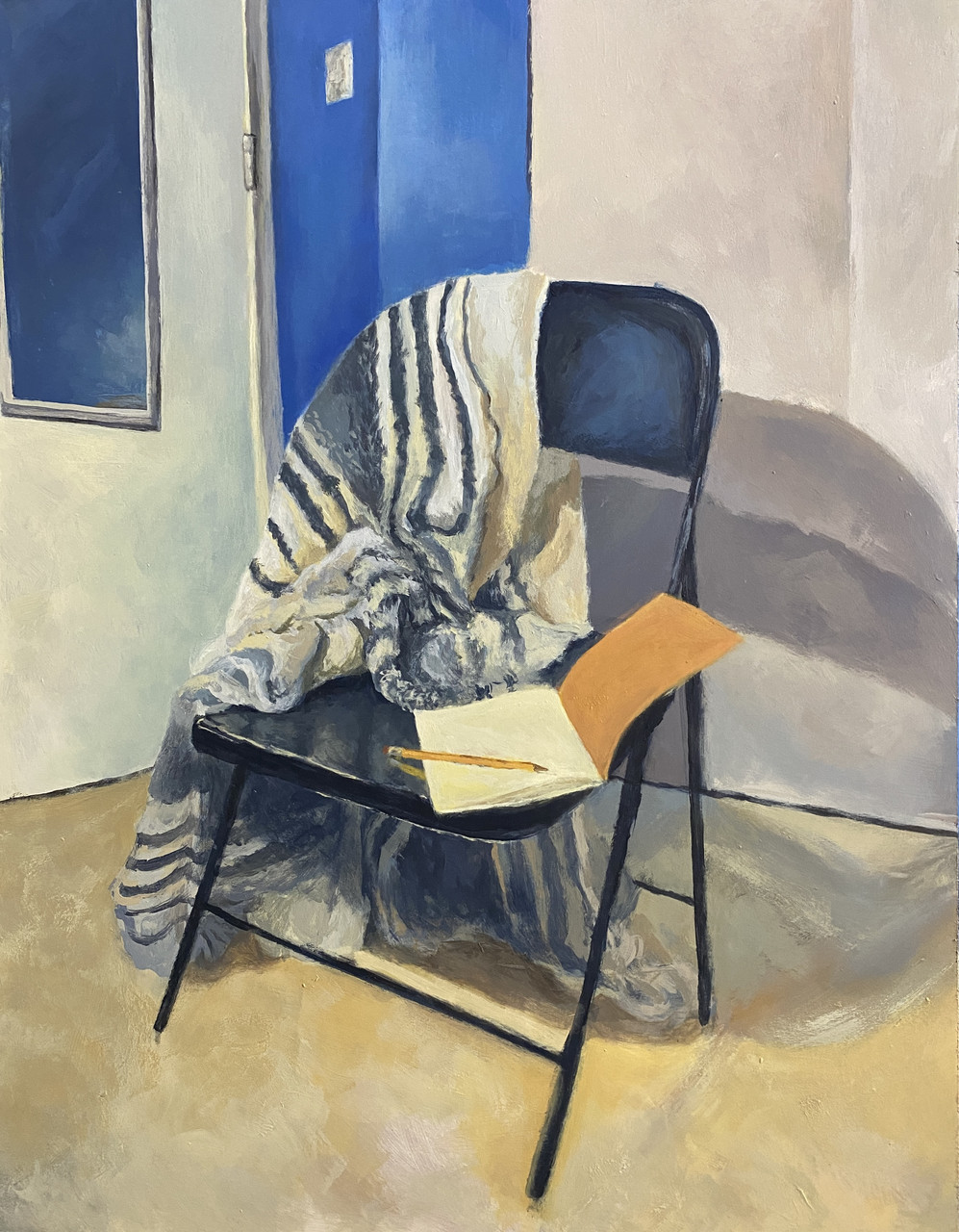 A chair with a blanket draped over the back, with a notebook and pencil on the seat.