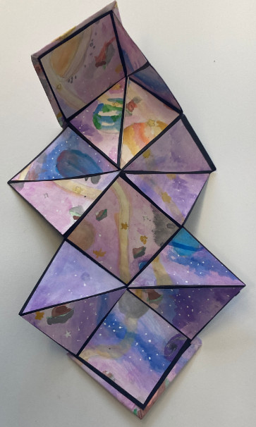 Galactic imagery juxtaposed on folded squares and triangles composing a larger piece.