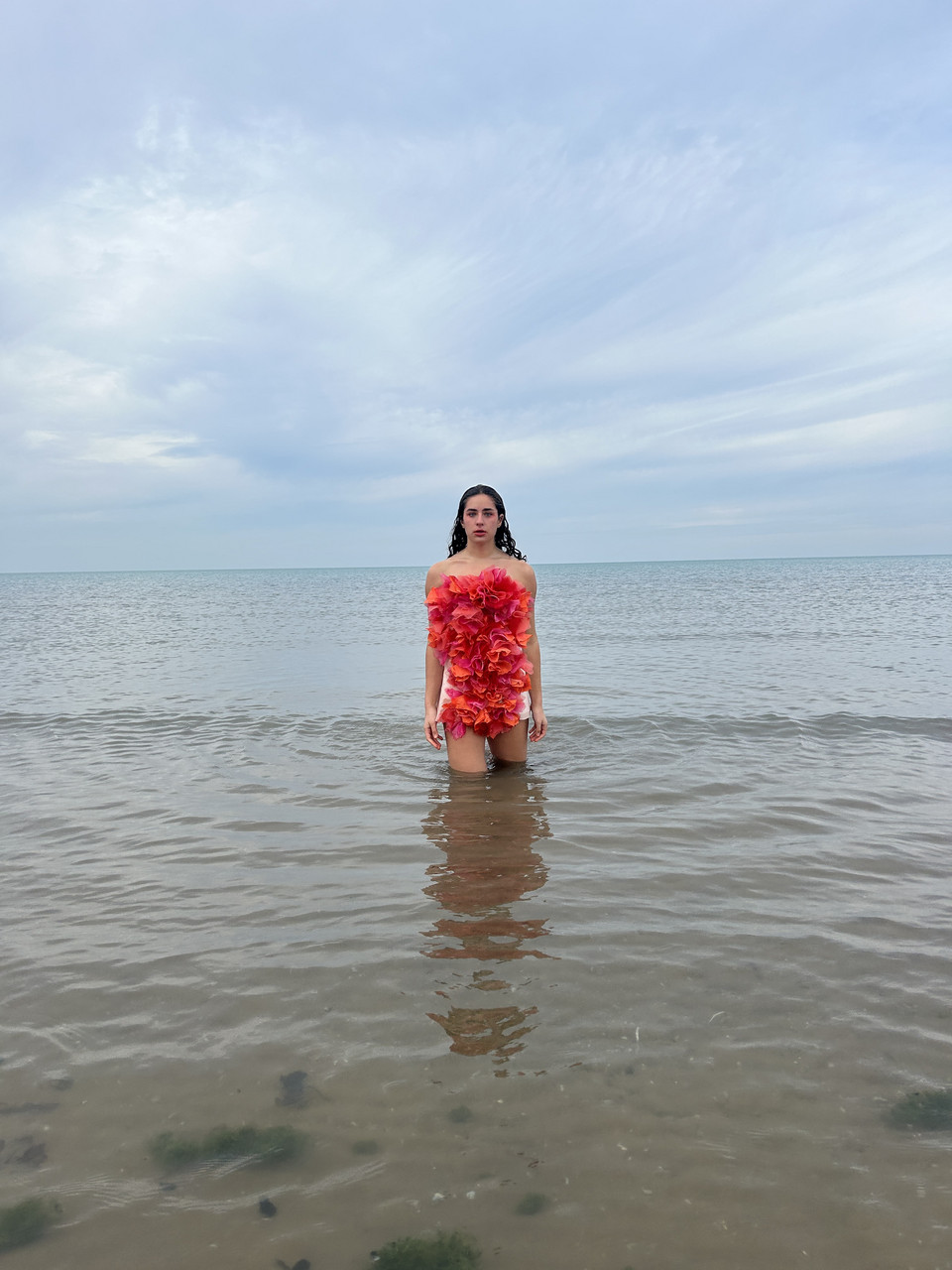 Female wearing a red scrunched up dress standing in a body of water