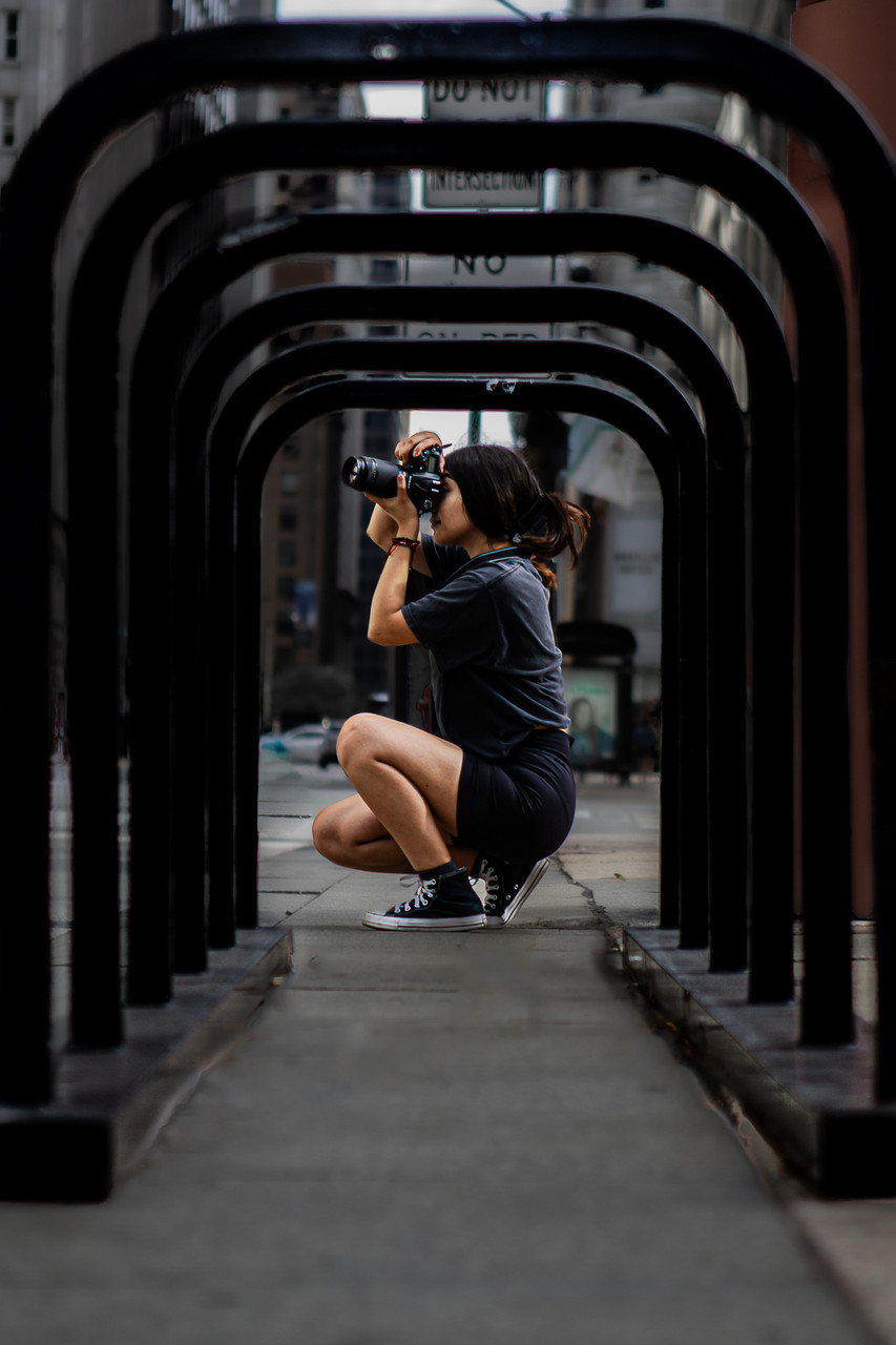 View of someone holding up a camera through a public bike rack