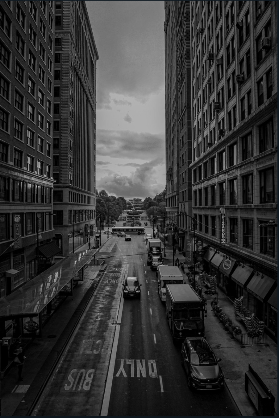 Black and white photogaph of busy street between tall buildings