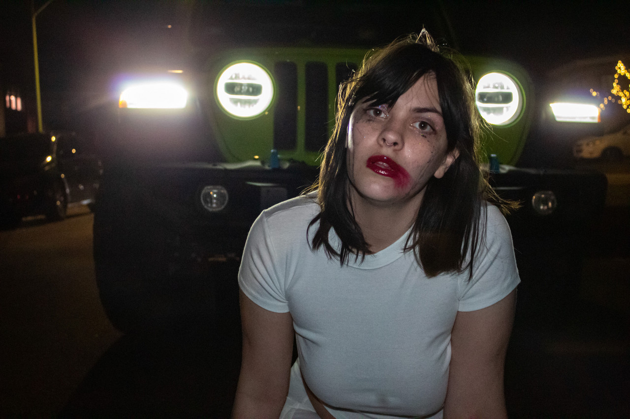 Woman with lipstick smeared over her lips with a white shirt in front of the camera.