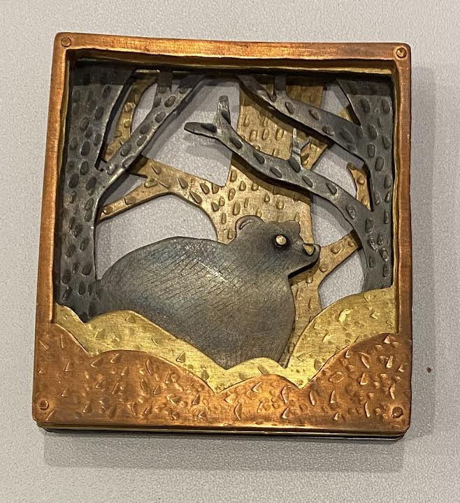 Mixed metals over layed to create a bear in front of three trees.