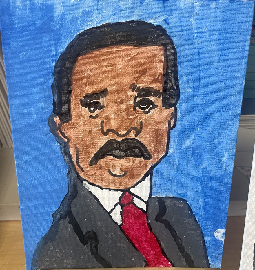 Portrait of man in in suit with red tie in front of a blue background.