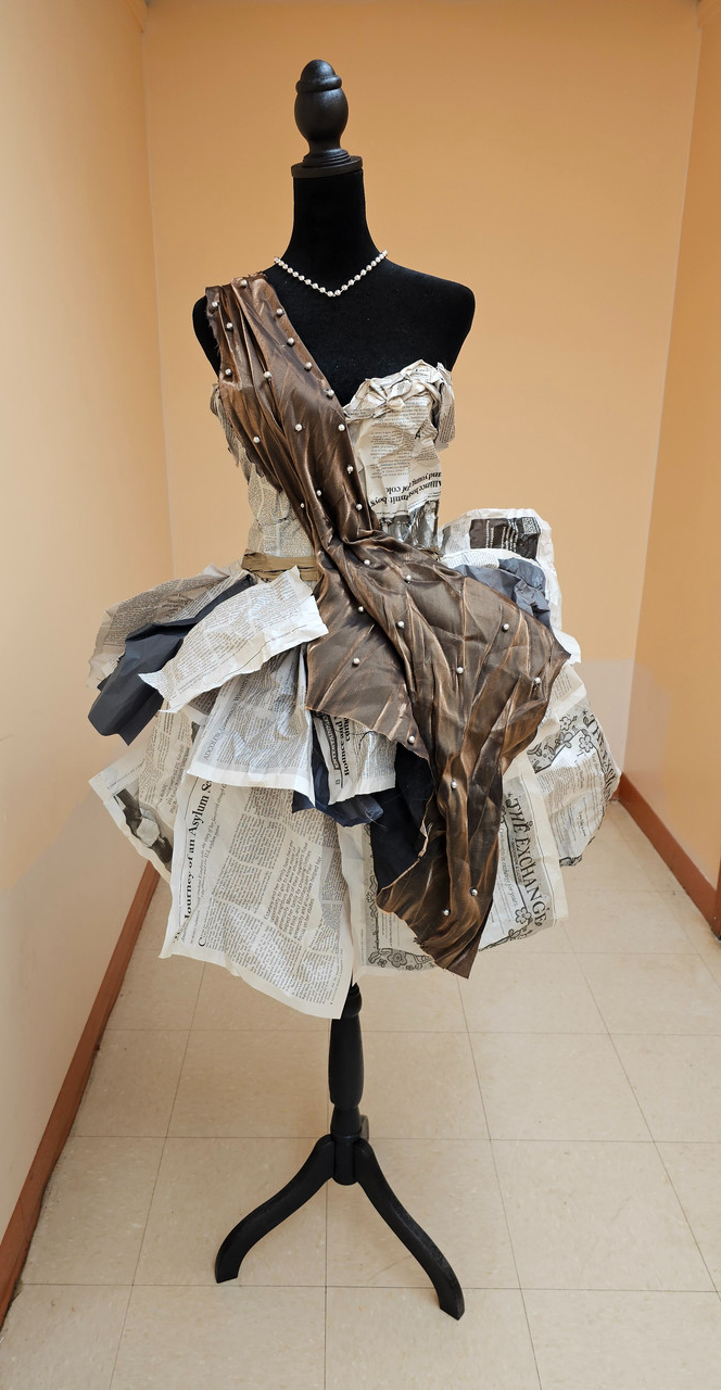 Dress on mannequin. Dress made of brown fabric and newspaper.