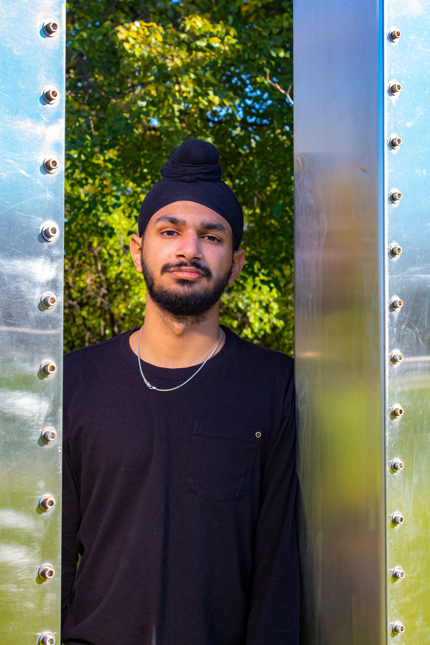 Photograph of a teenager in front of trees in between a steel structure.