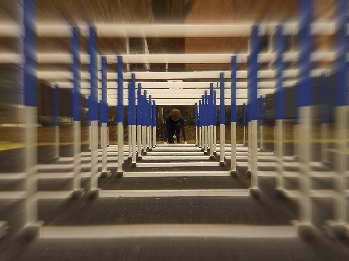 Track hurdles blur together. They frame the center where a person is crouching down