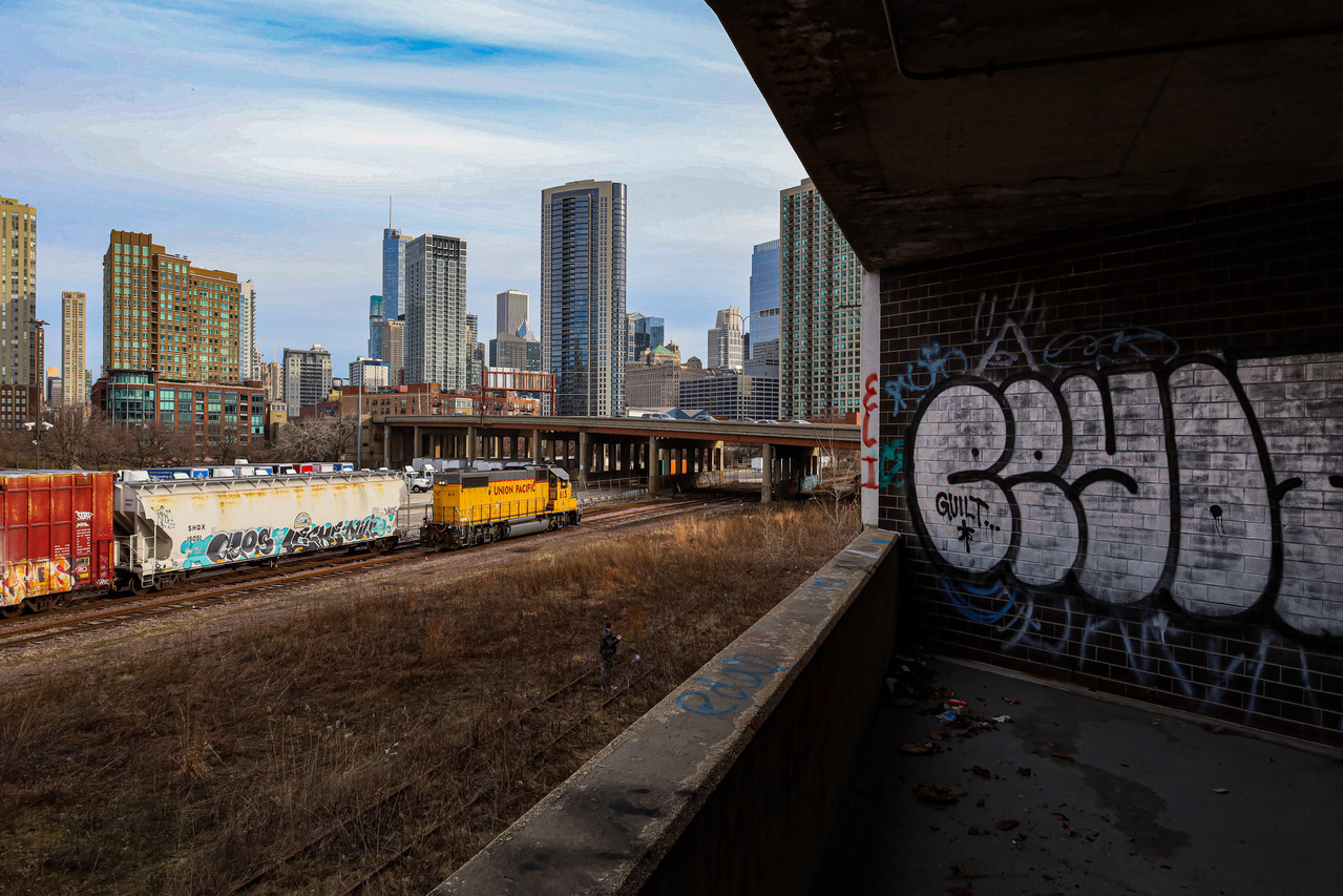 Photo of train station with train passing, skyline behind.
