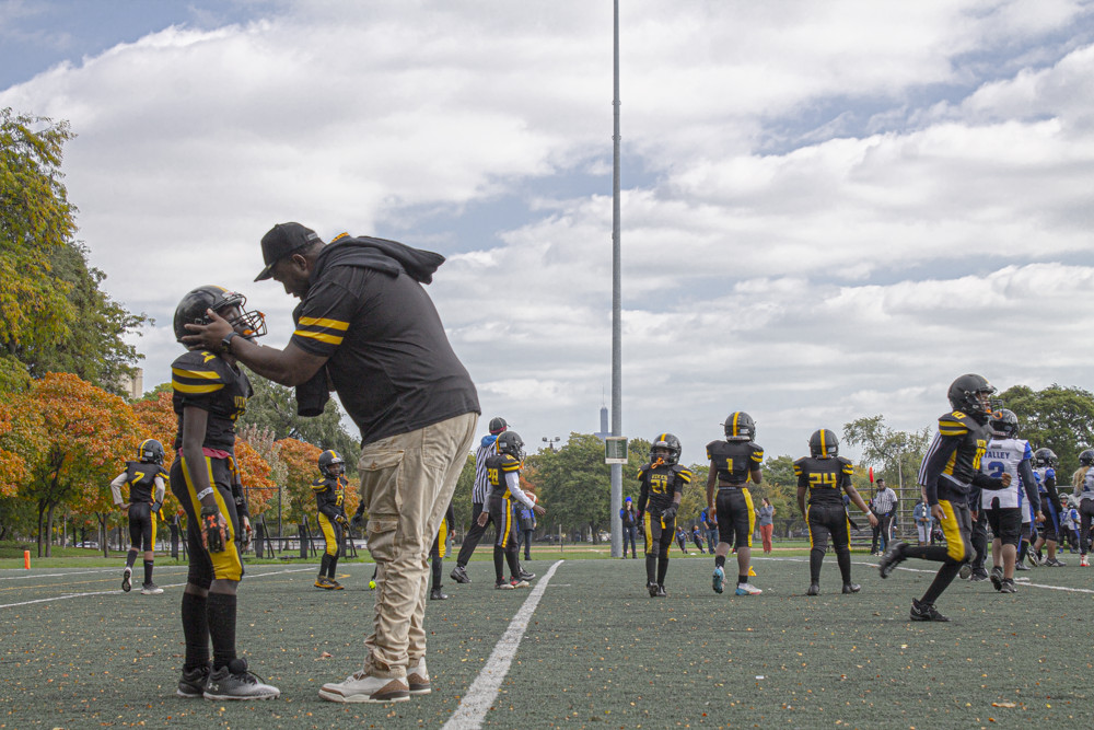 Photo of coach holding the head of a young football player on a football field.