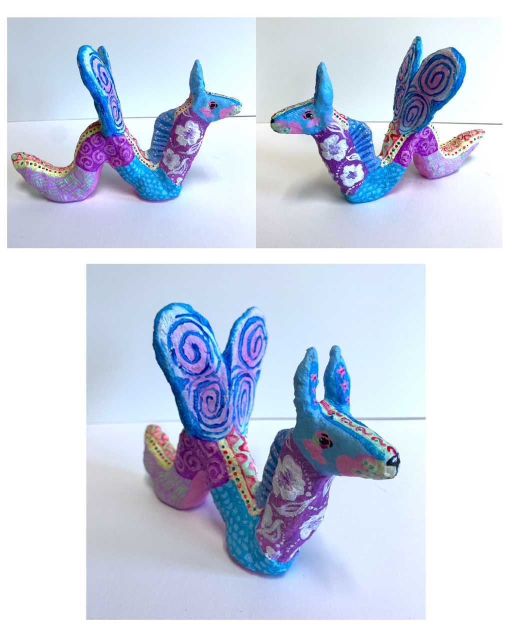 Sculpture of purple and blue treasure with wings and various colorful patterns. Wave-like body.