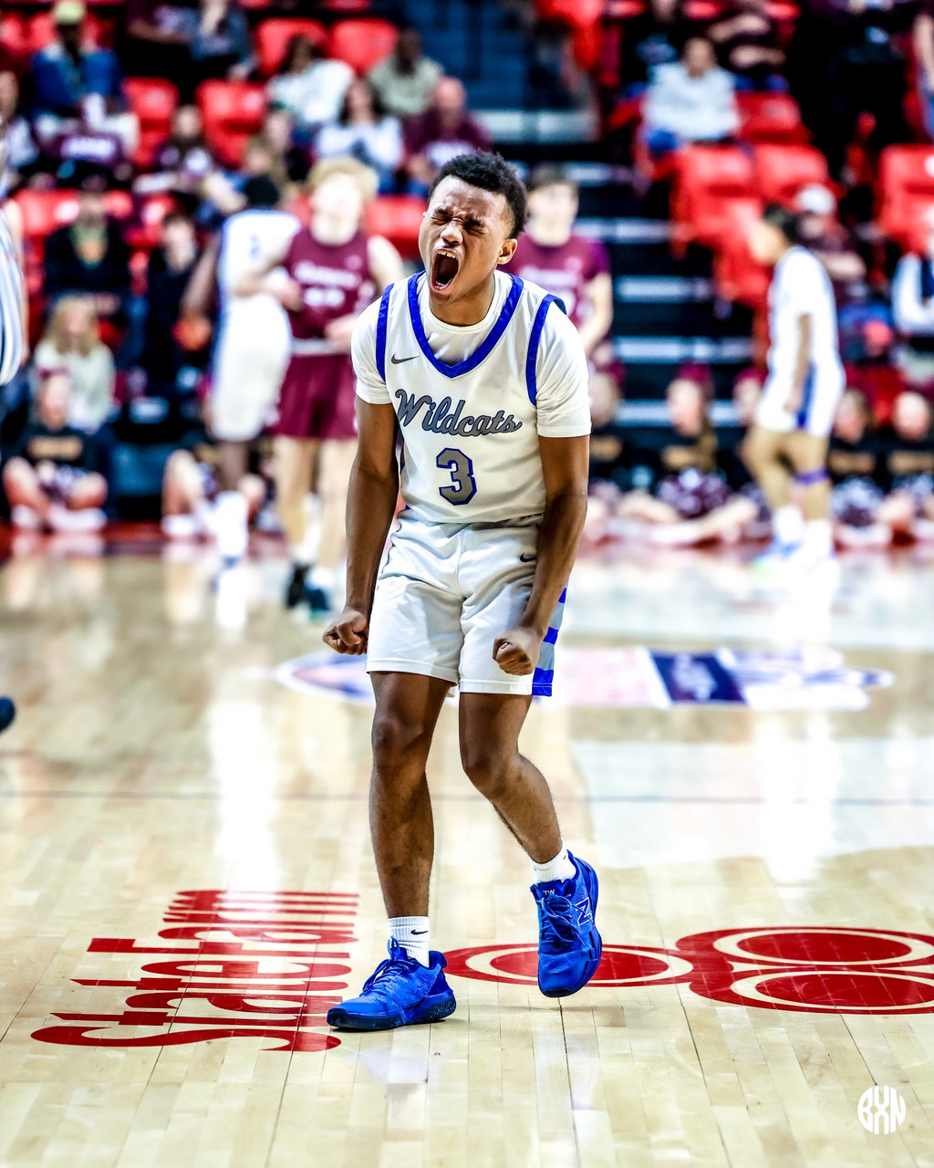 Photo of a basketball player celebrating. His mouth is open in clear passion on the court.