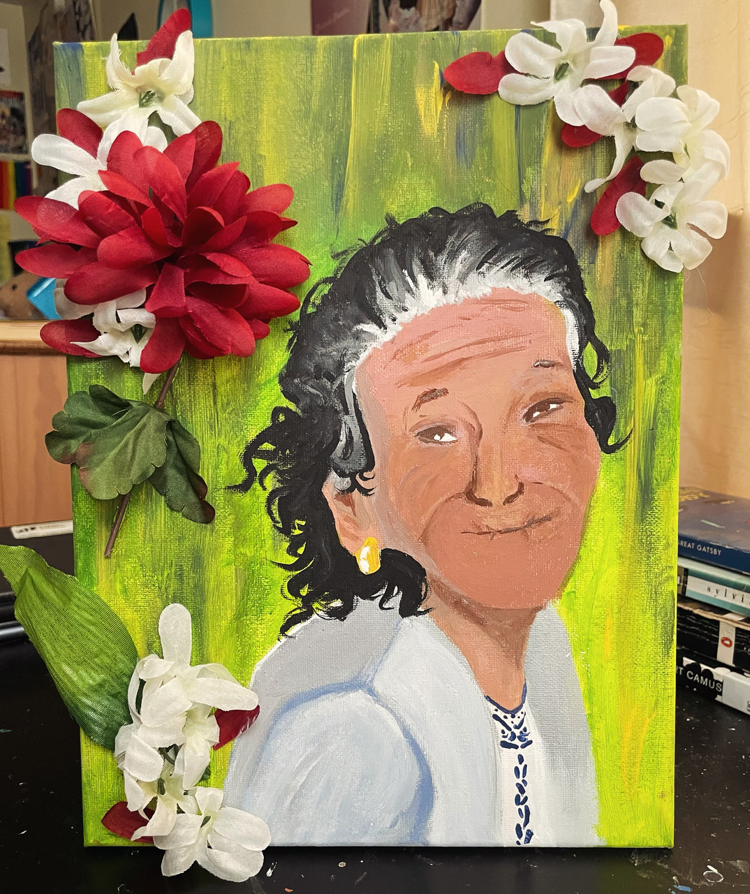 Older person in front of green background. Back ground is ornamented with faux red and white flowers.