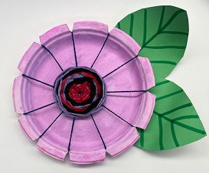 Pink flower made from a paper plate, paper, and yarn.