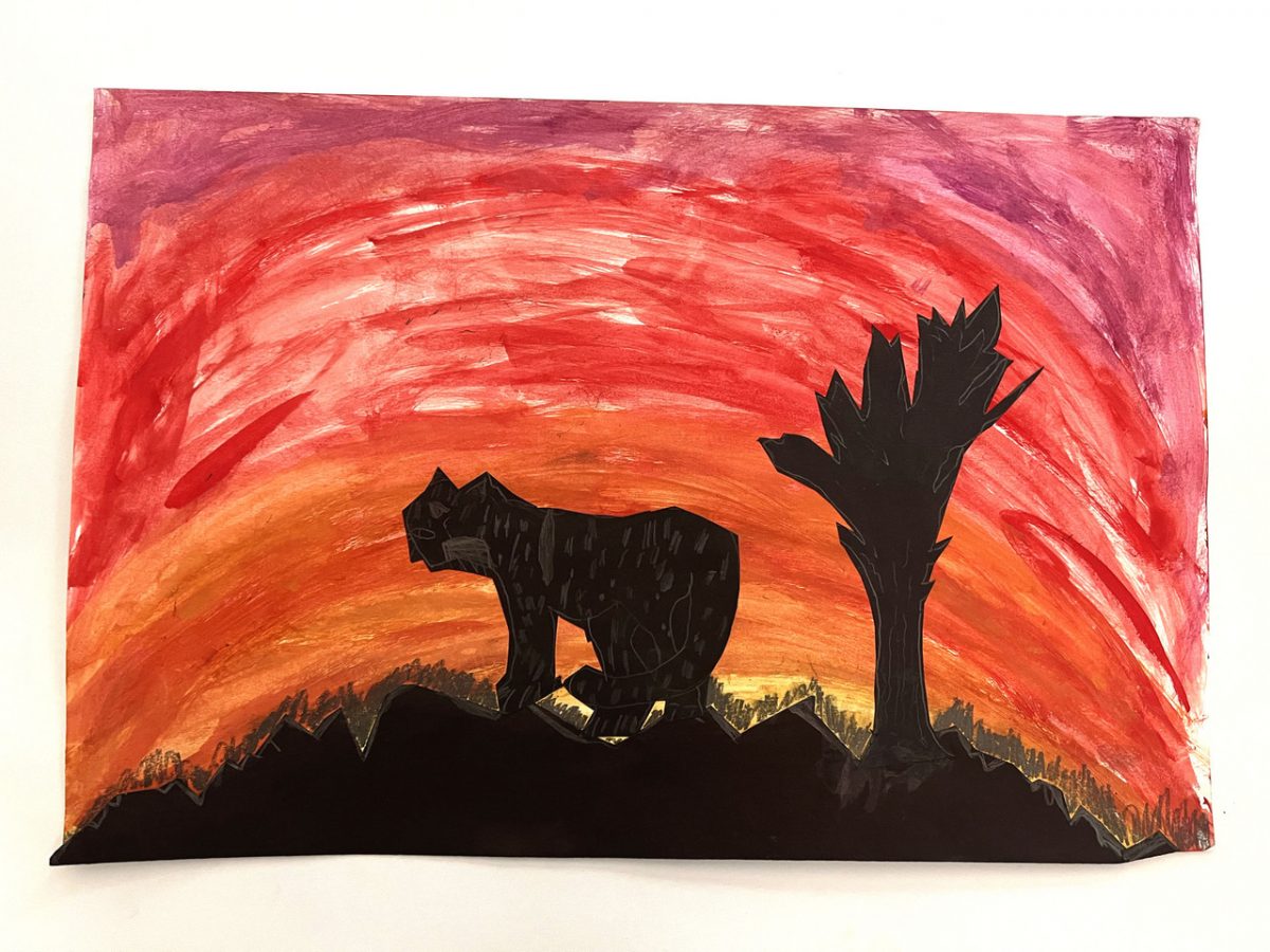 Animal silhouette stands in front of red and orange sky
