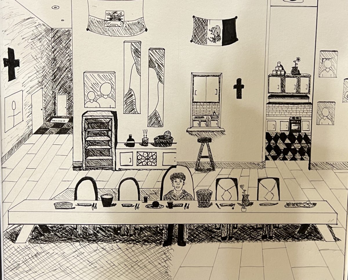 A man is the only one at a dinner table. In the background are the Haitian and Puerto Rican flags, a kitchen, and a cross
