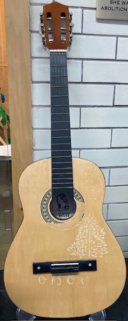 Carving of plant and words onto old acoustic guitar.