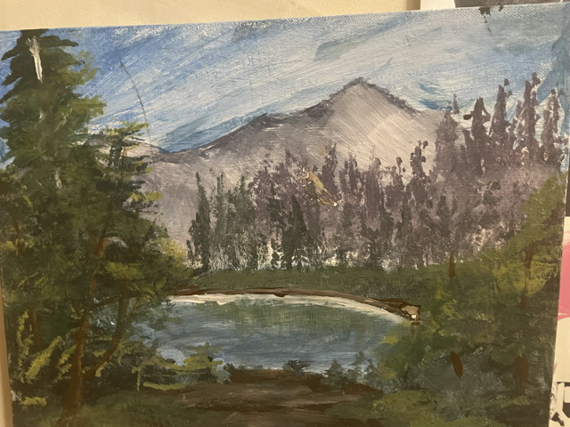 A landscape of a lake surrounded by pine trees and a mountain in the background