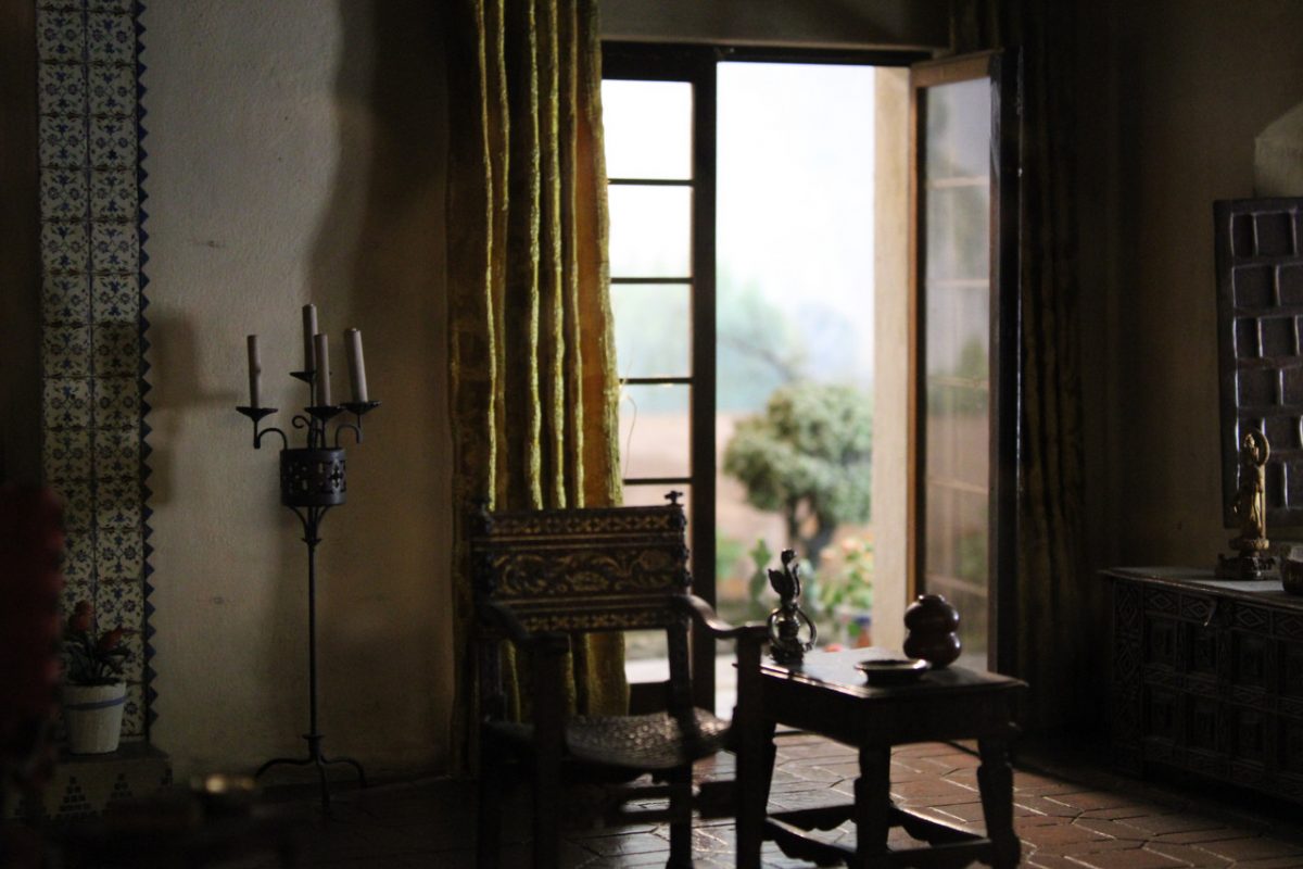 A ornate miniature room with a door open letting in light