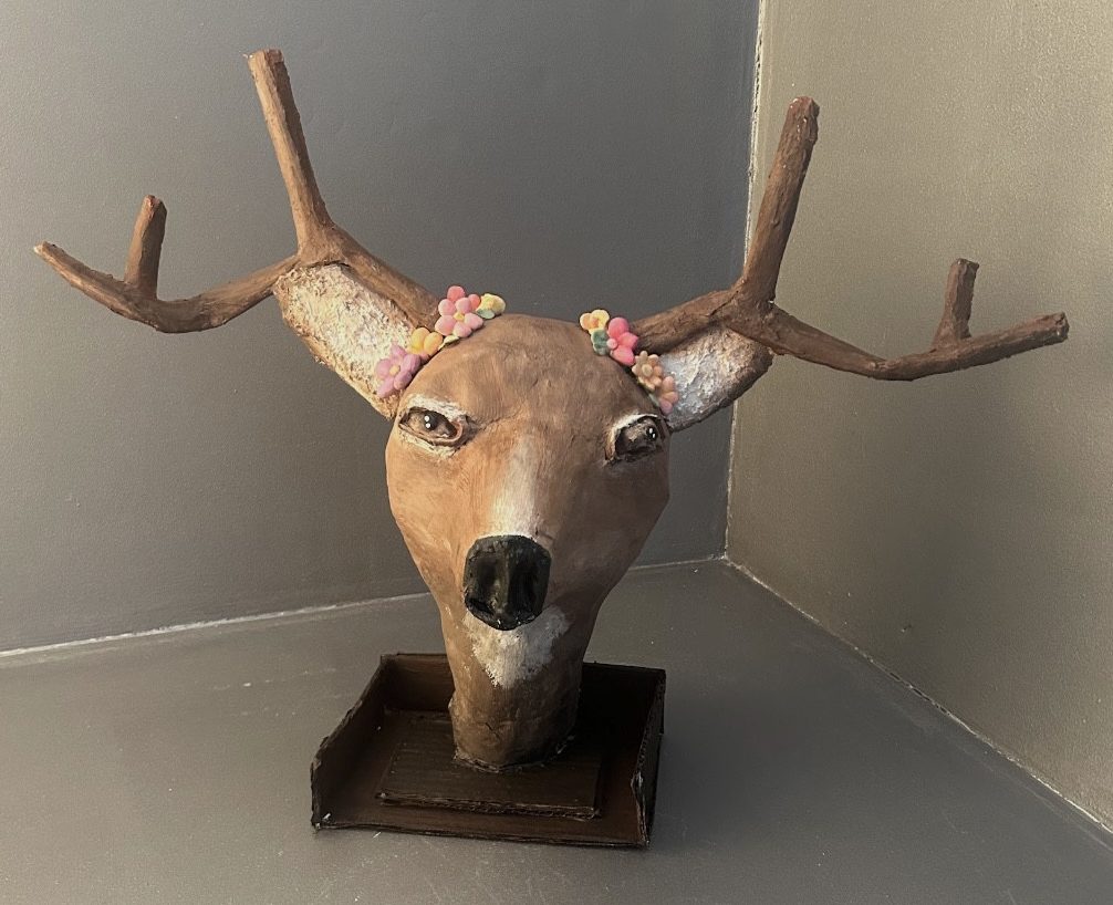 Sculpture of deer head with flowers near ears