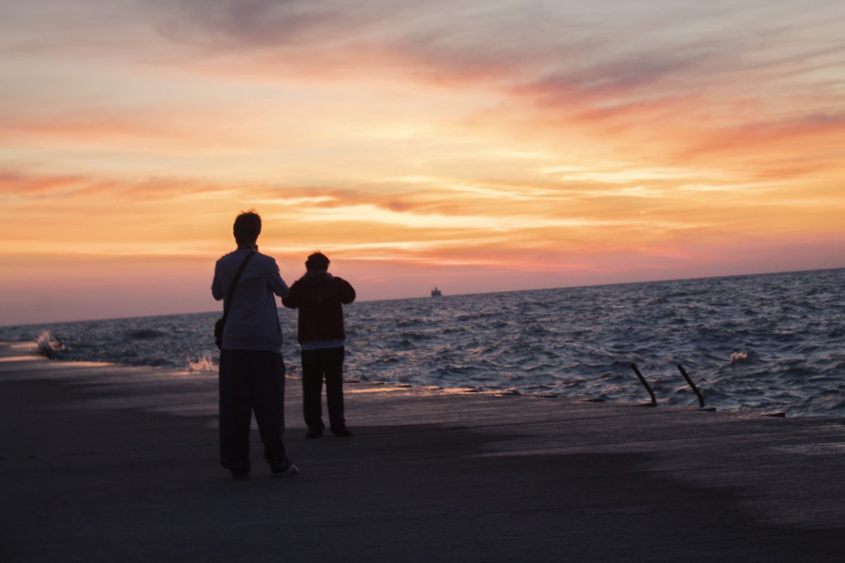 Photograph of sunrise over lake with two people in foreground