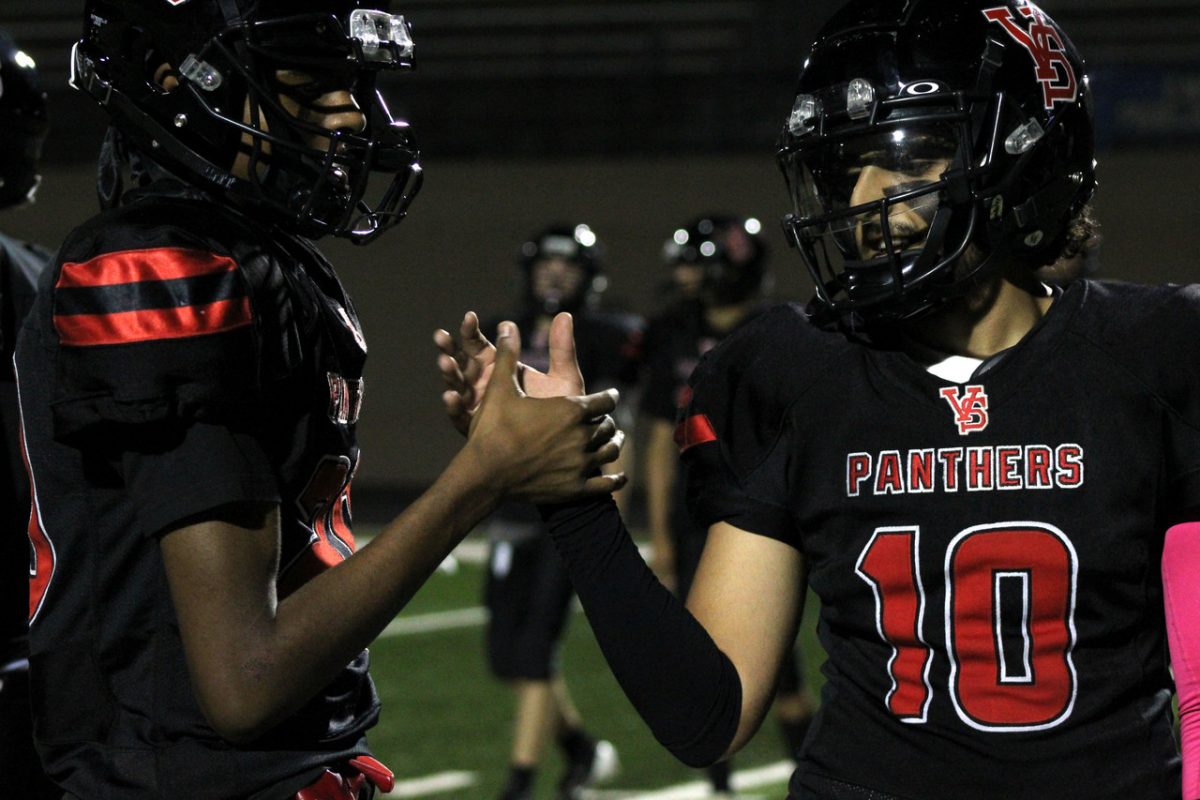 photograph of two football players in red and black jerseys and helmets shaking hands