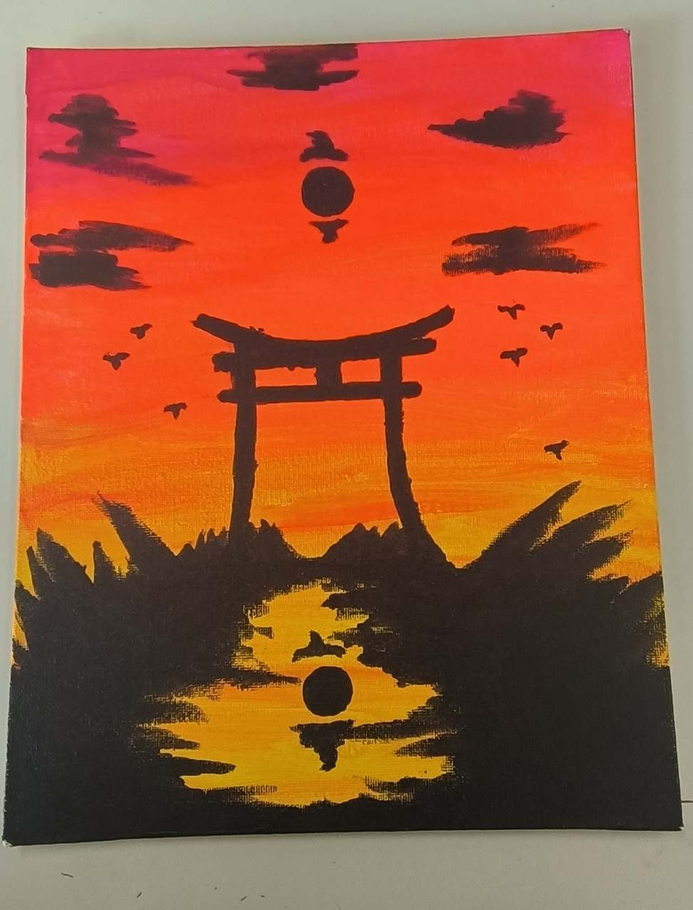 Painting of sunset on canvas with black sculpture and foliage in foreground