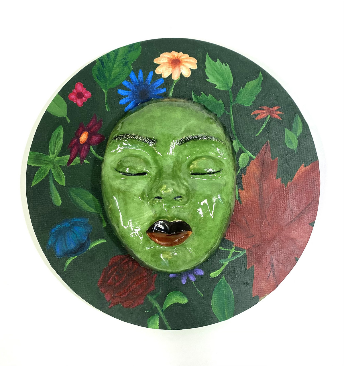 Green sculpture of face surrounded by multi-colored flowers