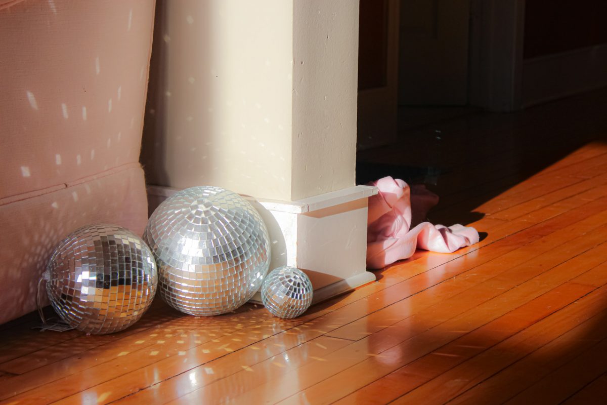 Photograph of three disco balls on wood floor reflecting