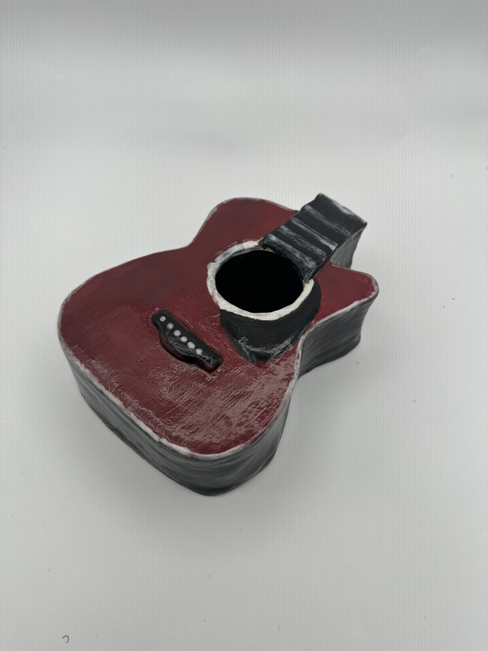 Photograph of ceramic sculpture of red guitar body with black features