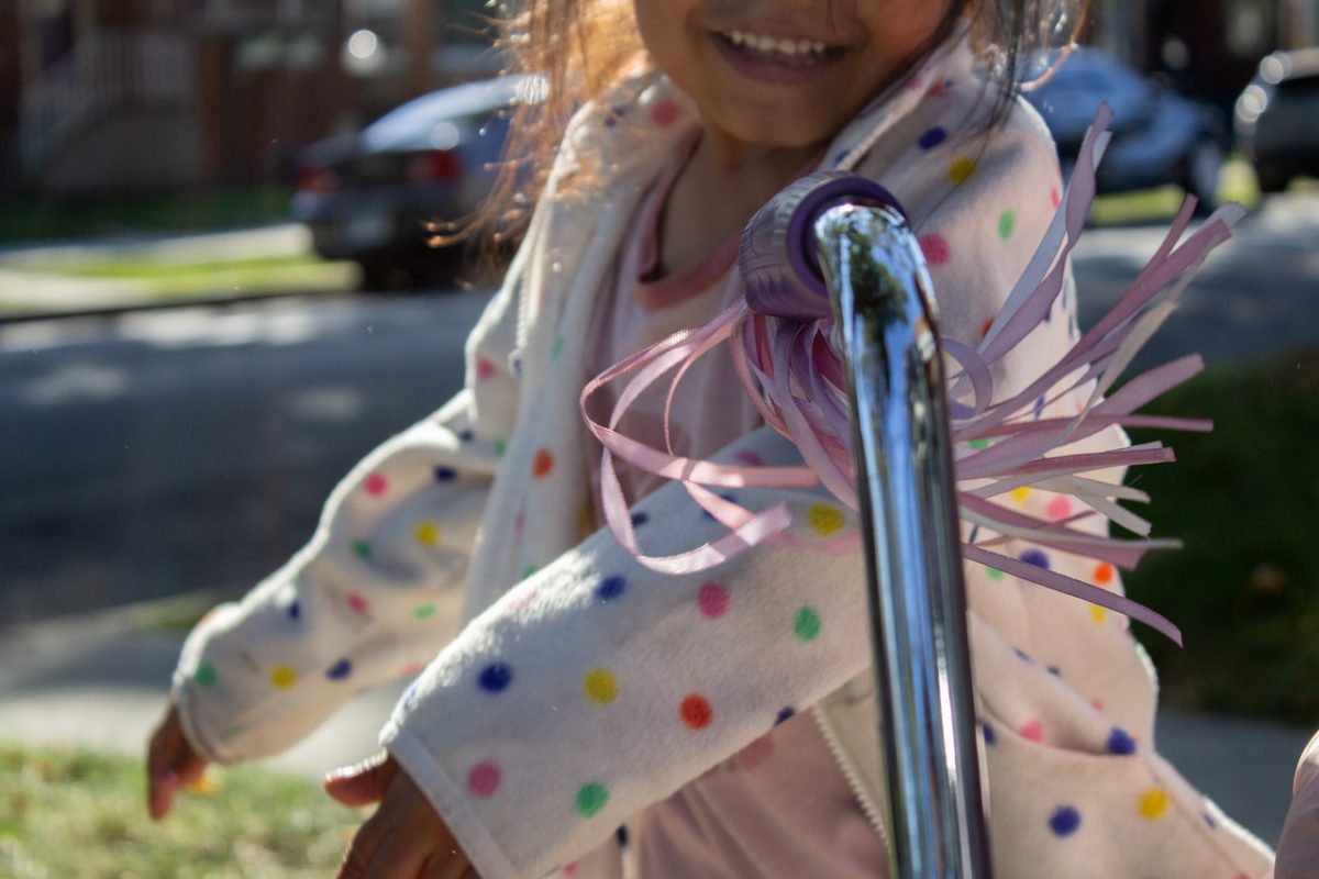 close up image of small child in polka dot shirt and bike handle with streamers