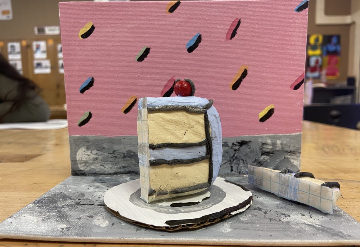 Mixed media art with pink background and 3 dimensional cake with blue icing, and yellow inside on a white plate