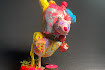 Image of multi-colored sculpture with yellow body and pink had with hat on