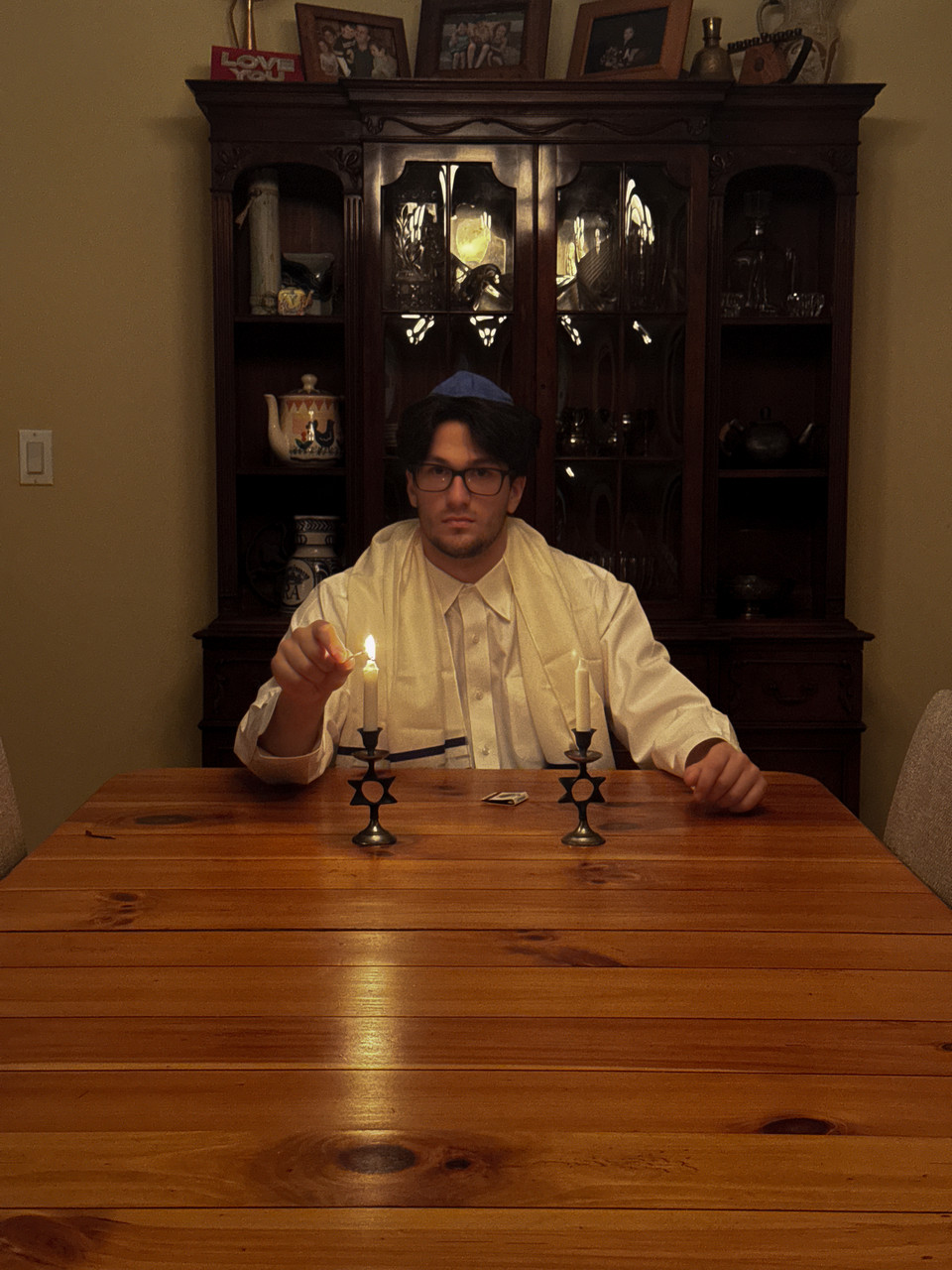 Photograph of man in traditional jewish dress lighting candle