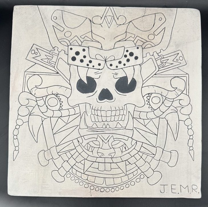 white tile with black image of skull with adornments