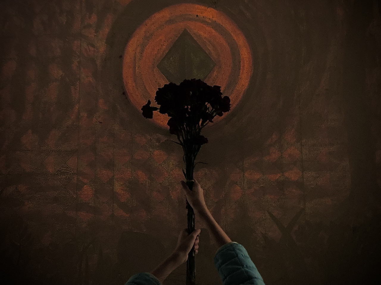 Photograph of hands holding up flowers with tan and orange background