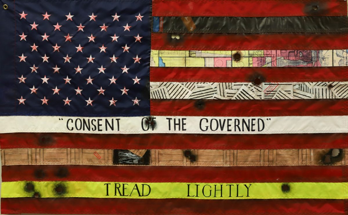 Mixed media art of american flag with altered portions showing different patterns and phrases, burns, and bullet holes, including text "Tread Lightly" and "Consent of the Governed"